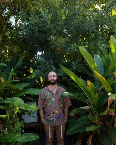 Aaron Stefansky standing barefoot on a boardwalk among dense tropical planting.